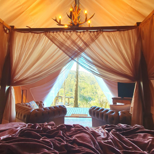 Cama king size com aquecimento e massagem no interior da tenda glamping Guardião da Montanha