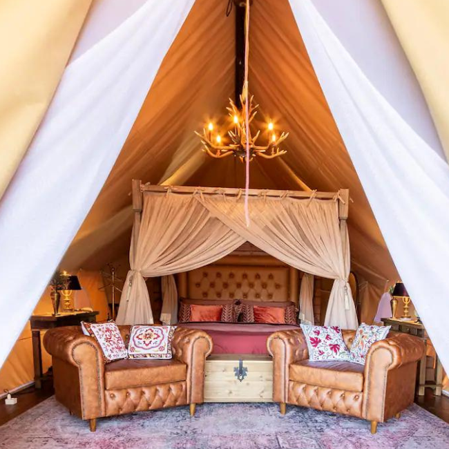 Interior da tenda glamping com cama king size aquecida e decoração rústica de luxo